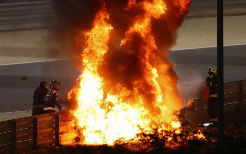 Fire marshals put out a fire on Haas F1's French driver Romain Grosjean's car during the Bahrain Formula One Grand Prix at the Bahrain International Circuit in the city of Sakhir on November 29, 2020 - BRYN LENNON 