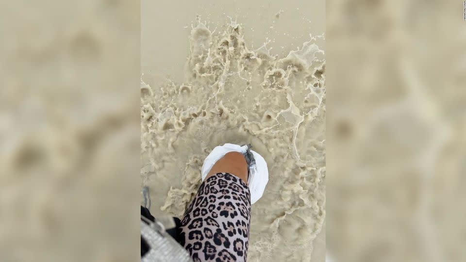 Burning Man attendee Masha Maltsava wears trash bags on her feet while walking through water at Burning Man on Saturday, September 2, 2023. - Masha Maltsava