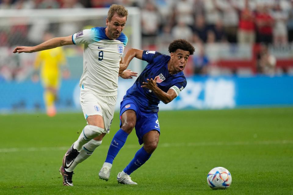 England's Harry Kane, left, challenges for the ball with Tyler Adams of the United States during the World Cup group B soccer match between England and The United States, at the Al Bayt Stadium.