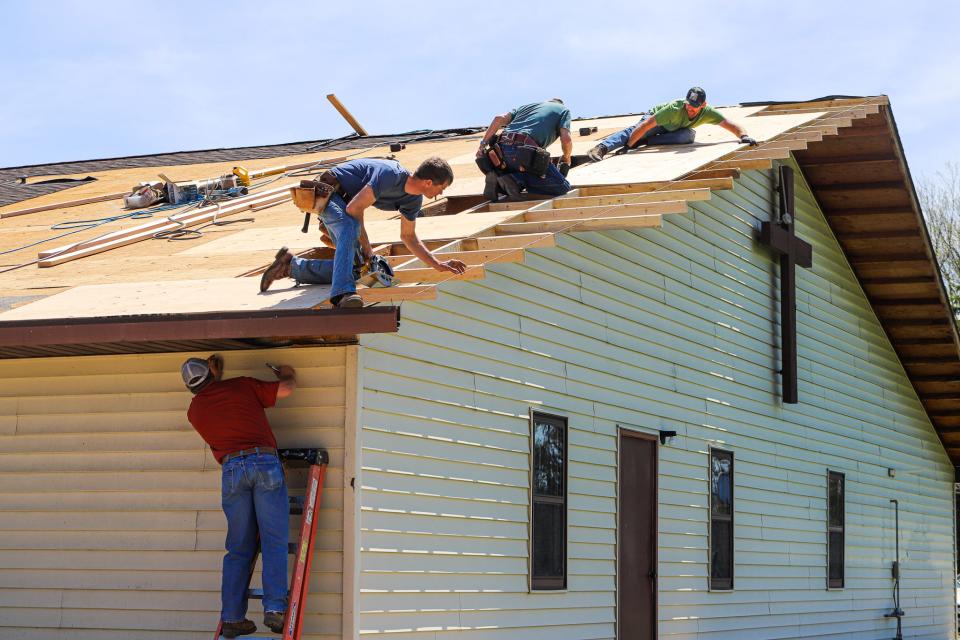 A crew of community members work to repair Calvary Free Lutheran Church in Arlington on May 13 after a major storm blew away the roof in two sections of the building the night before.