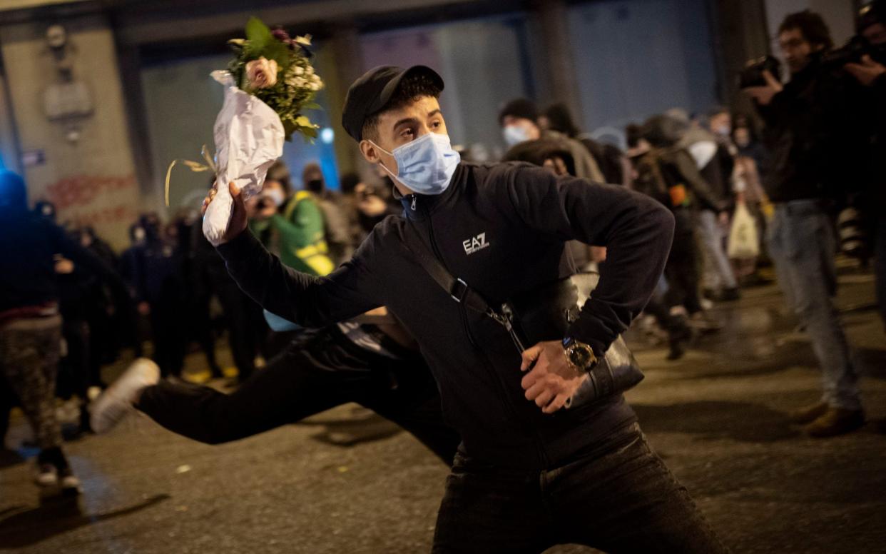 A man throws a bouquet of flowers against a national police station during a protest - Emilio Morenatti /AP