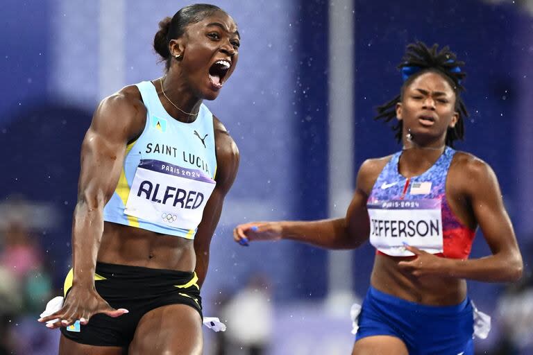 Julien Alfred de Santa Lucía celebra después de ganar la la final femenina de 100 metros; la escolta la estadounidense Melissa Jefferson (R) 