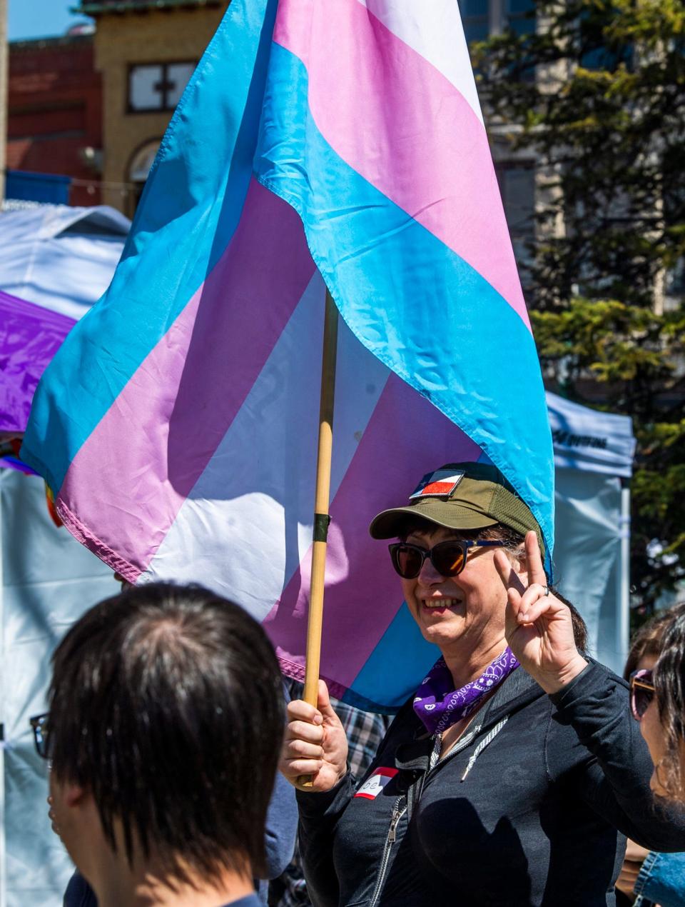 Holding a transgender flag, Elbe Lieb shows a peace sign during the "End hate, elevate and celebrate trans joy" demonstration at the Monroe County Courthouse on Sunday, April 2, 2023.