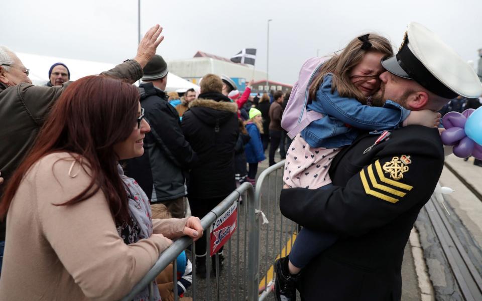 Petty Officer Adam Jeffrey (right) is greeted by his daughter Isabelle, 5, and wife Luisa (left) after coming ashore from HMS Ocean - Credit: Andrew Matthews/PA