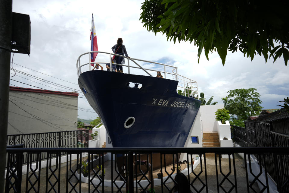 Tourists pose on Sunday, Oct. 23, 2022, for a picture on top of the bow of M/V Eva Jocelyn, at the coastal village of Anibong, an area badly hit by super Typhoon Haiyan when it struck the province nine years ago, in Tacloban city, central Philippines. The ship was swept ashore during the height of super Typhoon Haiyan that left thousands dead or missing in central Philippines and destroyed homes, agriculture and infrastructure and left thousands homeless. (AP Photo/Aaron Favila)