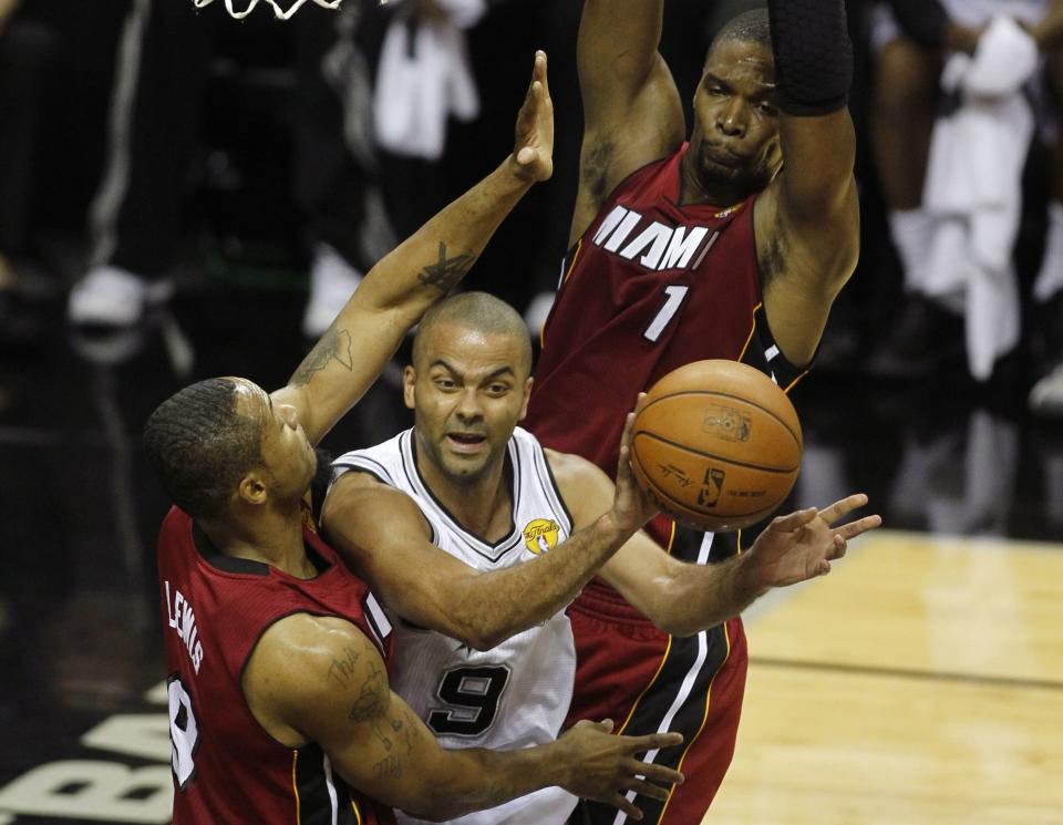 San Antonio Spurs' Tony Parker (C) of France passes as he is defended under the basket by Miami Heat's Rashard Lewis (L) and Chris Bosh during the first quarter in Game 1 of their NBA Finals basketball series in San Antonio, Texas June 5, 2014. REUTERS/Mike Stone (UNITED STATES - Tags: SPORT BASKETBALL)