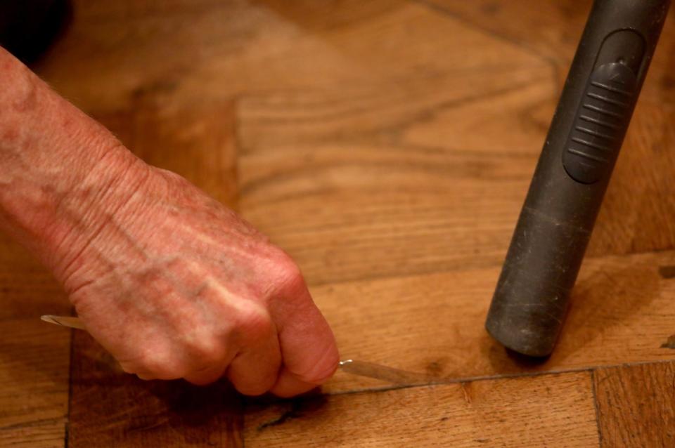 Close-up of hands using a small spatula and vacuum.