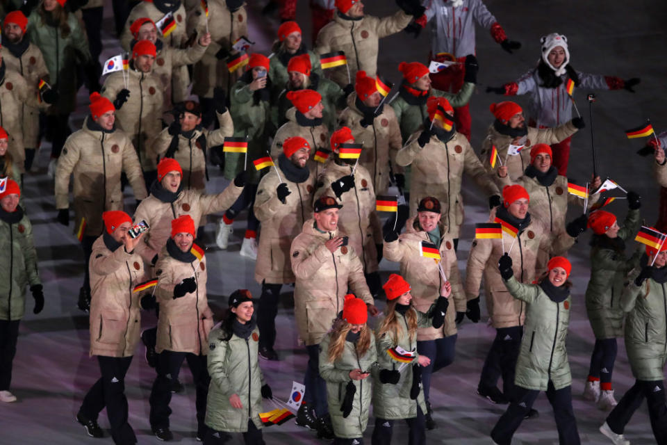 <p>German athletes emerge for the parade wearing khaki-color puffer jackets, black pants, and crimson beanies during the opening ceremony of the 2018 PyeongChang Games. (Photo: Sean M. Haffey/Getty Images) </p>
