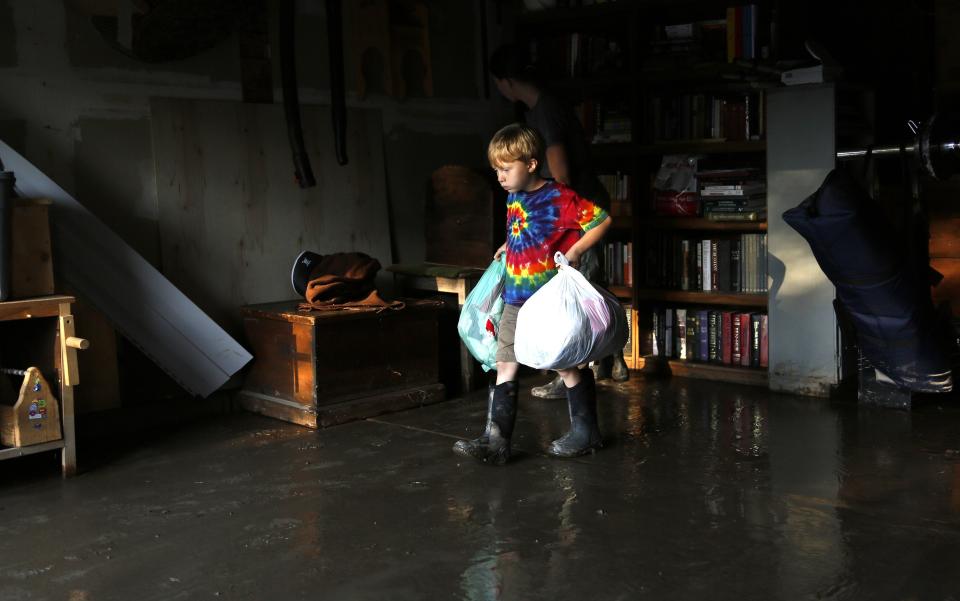 Rowen Roberson carries clothes from his flooded garage in Longmont, Colorado September 16, 2013. (REUTERS/Rick Wilking)