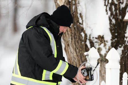 An Environmental Testing Associates employee checks an air monitor attached to the fence of a home in Boomer, West Virginia on Tuesday, February 17, 2015. REUTERS/Marcus Constantino