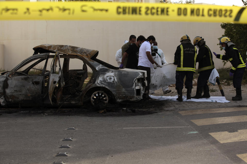 Civil defense workers remove a body from a burned-out car in Mughsha, Bahrain, Saturday, April 19, 2014. Authorities in Bahrain say an apparent car bombing has killed two people and wounded one west of the capital, Manama. Bahrain has been roiled by three years of unrest, with a Shiite-dominated opposition movement demanding greater political rights from the Sunni monarchy. (AP Photo/Hasan Jamali)