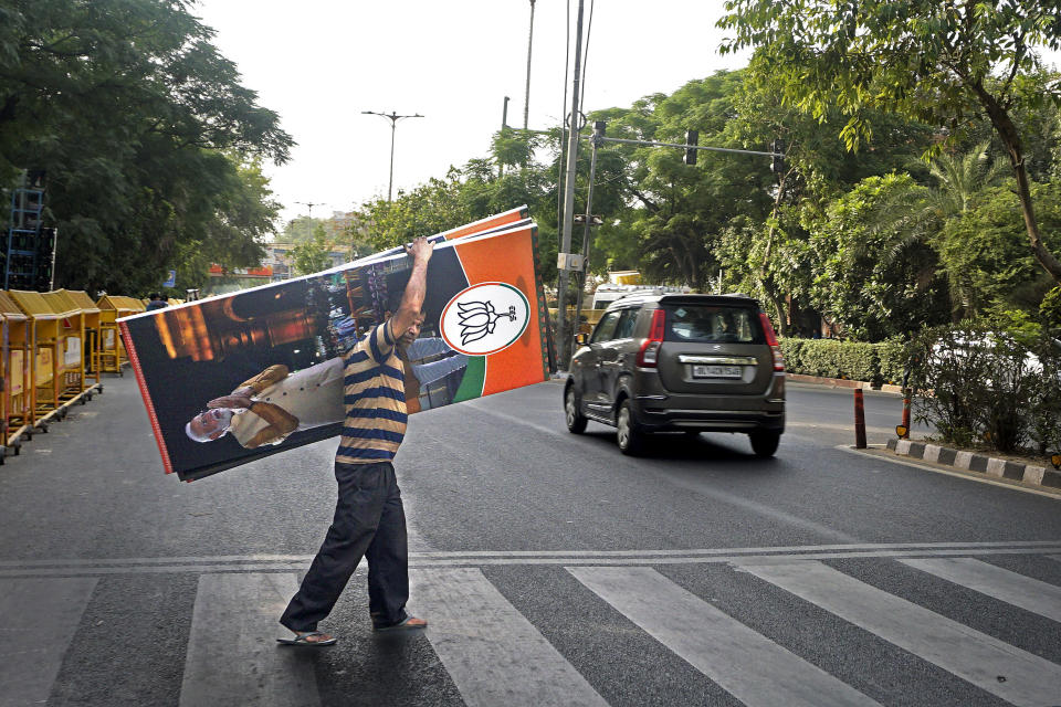 A worker carries a banner of Bharatiya Janta party featuring Indian Prime Minister Narendra Modi to be put up outside party headquarters in New Delhi, India, Tuesday, June 4, 2024. India began counting more than 640 million votes Tuesday in the world's largest democratic exercise, which was widely expected to return Prime Minister Narendra Modi to a third term after a decade in power. (AP Photo/Dinesh Joshi)