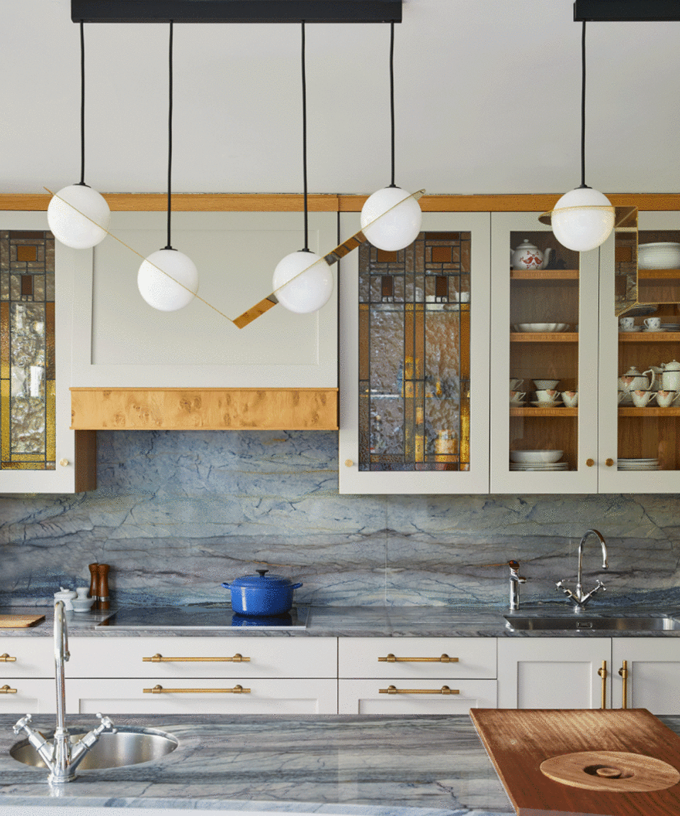 Pale kitchen with glass cabinetry, grey marble and large statement light