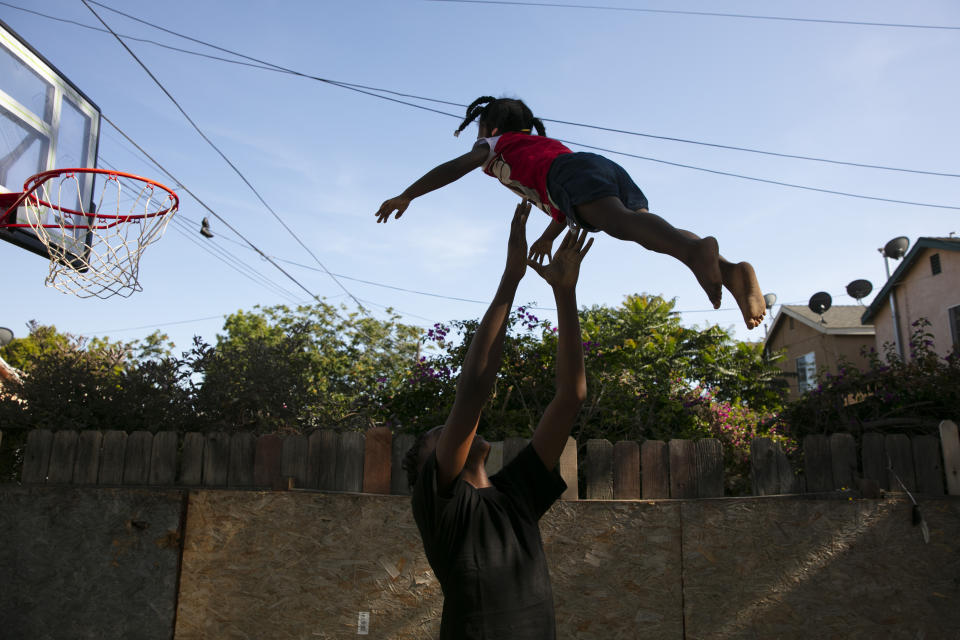 James Posey III, 14, tosses a neighbor's kid in the air while playing with her in the Watts neighborhood of Los Angeles, Monday, June 15, 2020. Watts has long been associated with deadly and destructive rioting in 1965. This summer when widespread mostly peaceful protests for racial justice across the U.S. have been accompanied at times by vandalism and other crimes, Watts has been peaceful. One lawmaker says the residents learned long ago that it didn't pay to burn their own neighborhood. (AP Photo/Jae C. Hong)