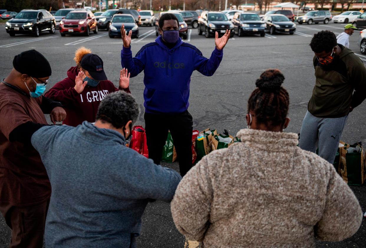 Pastor Jerome Allen Bell (C) leads a prayer before a pre-Thanksgiving food handout, sponsored by resident Linda Flowers, for members of the community in Fort Washington, Maryland on Nov. 20, 2020.