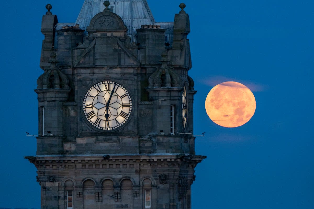 A supermoon sets behind the Balmoral Clock in Edinburgh (Jane Barlow / PA)