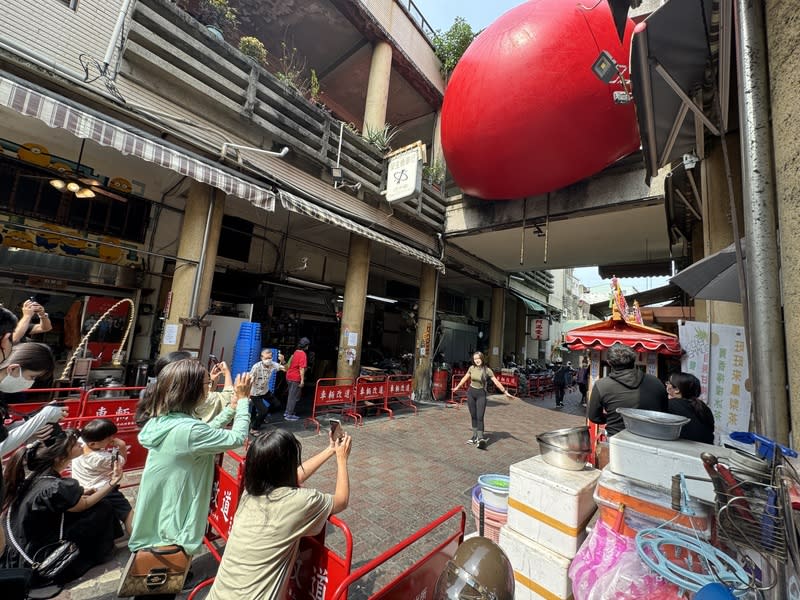 美國藝術家波希克（Kurt Perschke）發起「紅球計畫RedBall Project」，30日移展台南中西區永樂市場，除排隊搶食饕客外，不少國內外遊客高舉手機拍攝紅球。（中央社）
