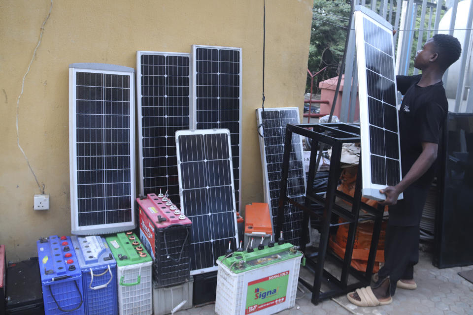 A man displays solar panels for sale outside a shop in Abuja, Nigeria, Saturday June 17, 2023. Nigeria's removal of a subsidy that helped reduce the price of gasoline has increased costs for people already struggling with high inflation. But it also potentially accelerates progress toward reducing emissions in Africa's largest economy. (AP Photo/Olamikan Gbemiga)