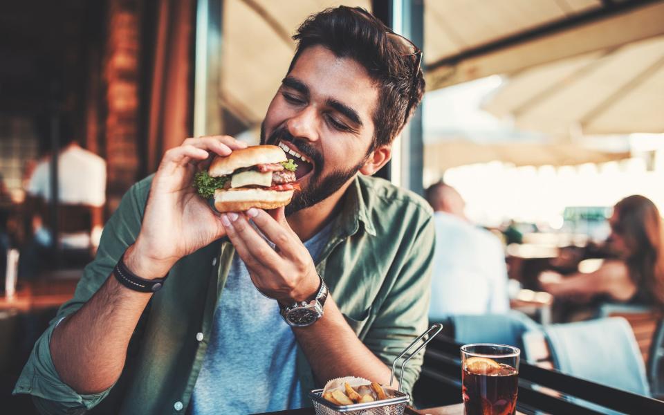 A man enjoying a sandwich in a cafe during a lunch break.