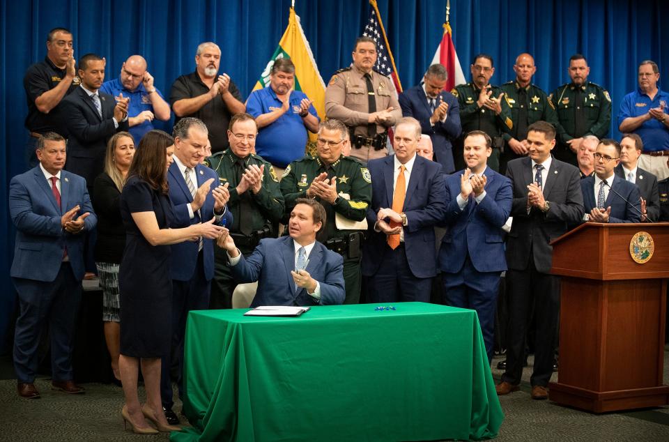 Florida Governor Ron Desantis hands a blue sharpie to Florida Attorney General Ashley Moody  after he signed a bill Combating Public Disorder during a signing ceremony at the Polk County Sheriff's Operation Center in Winter Haven Fl. Monday April 19 2021.  ERNST PETERS/ THE LEDGER