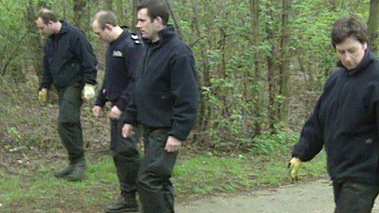 Police pictured searching woods after the discovery of the baby 