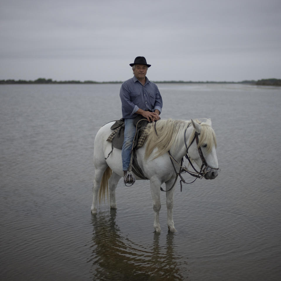 Frederic Raynaud poses for a portrait with his horse Greco at the beach next to his ranch in the Camargue, southern France, Oct. 19, 2022. Raynaud's pastures are slowly sinking into the sea as the sea level rises and higher soil salt levels render the land useless for growing agriculture or breeding animals. (AP Photo/Daniel Cole)