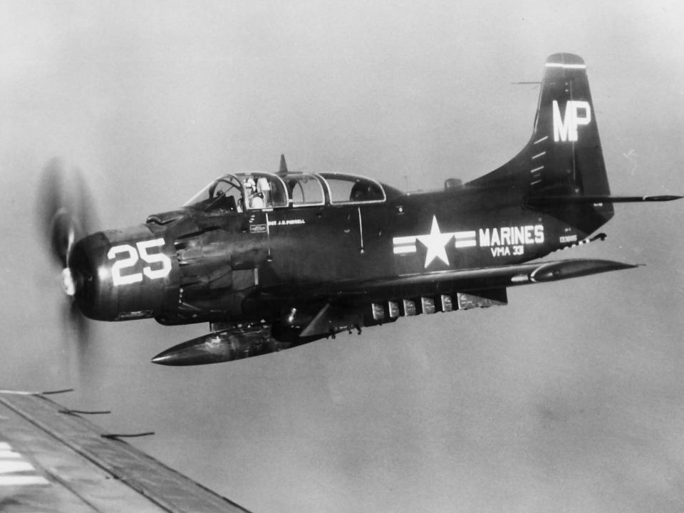 A black and white picture of a Marine Corps Douglas AD-5 Skyraider as seen from the window of another aircraft.
