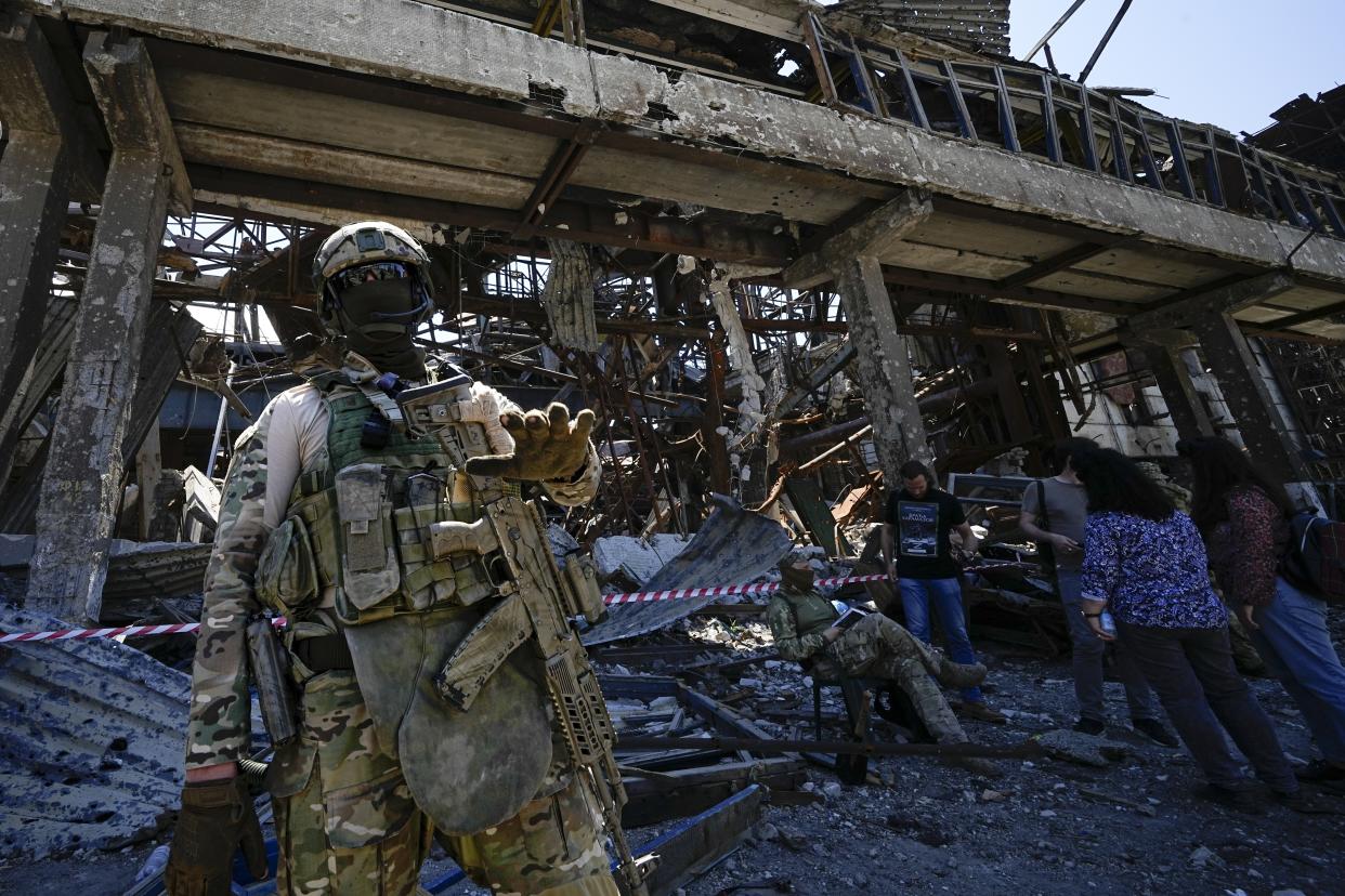 FILE - A Russian soldier speaks to foreign journalists in front of the ruined Metallurgical Combine Azovstal, in Mariupol, on the territory which is under the Government of the Donetsk People's Republic control, eastern Ukraine, Monday, June 13, 2022. Despite getting bogged down in Ukraine, the Kremlin has resisted announcing a full-blown mobilization, a move that could prove to be very unpopular for President Vladimir Putin. That has led instead to a covert recruitment effort that includes trying to get prisoners to make up for the manpower shortage. This photo was taken during a trip organized by the Russian Ministry of Defense. (AP Photo, File)