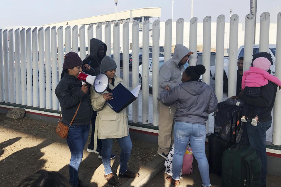 In this Nov. 12, 2019, photo, volunteers call names of people on a waiting list trying to obtain asylum in the United States along the U.S.-Mexico border in Tijuana, Mexico. The U.S. has sent a Honduran migrant back to Guatemala in a move that marked a new phase of President Donald Trump’s immigration crackdown. (AP Photo/Elliot Spagat)