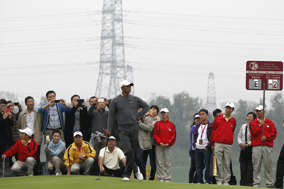 Fans take photos as Tiger Woods of the United States follows a drive by Rory McIlroy of Northern Ireland during their 18-hole medal-match at the Lake Jinsha Golf Club in Zhengzhou, in central China's Henan province, Monday, Oct. 29, 2012. Rory McIlroy shot a 5-under 67 to beat Tiger Woods by one stroke in a head-to-head, 18-hole exhibition match between the world's two top-ranked golfers. (AP Photo/Alexander F. Yuan)