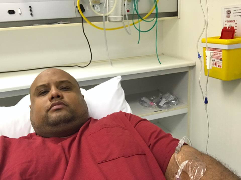 A man in a hospital bed wearing a red shirt