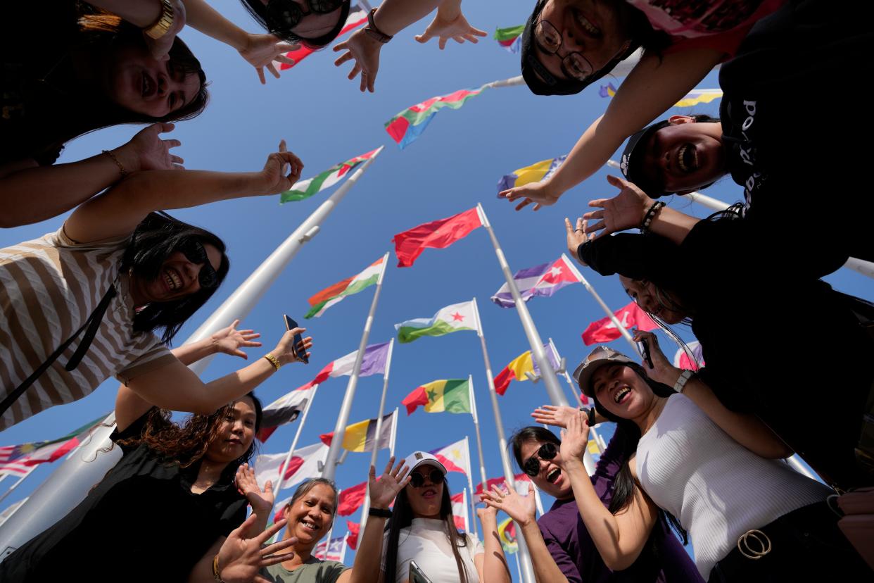 Fans cheer as they pose for a photograph at flag plaza in Doha, Qatar, Friday, Nov. 11, 2022. Final preparations are being made for the soccer World Cup which starts on Nov. 20 when Qatar face Ecuador. (AP Photo/Hassan Ammar)