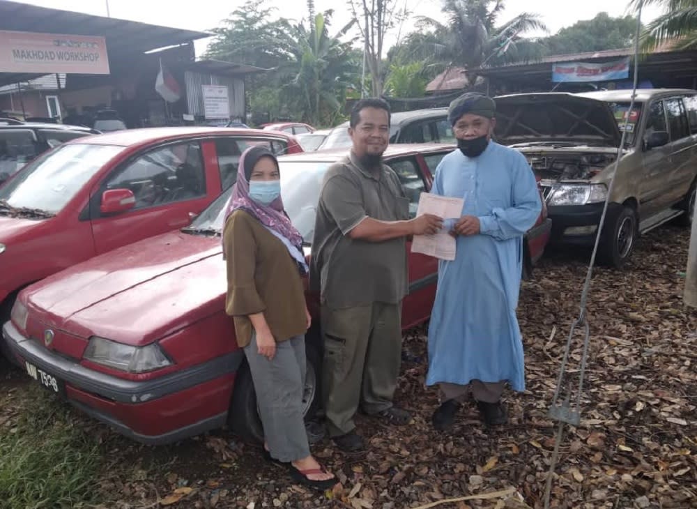 Shikh Muhammad (centre) felt elated after selling the second-hand Proton Iswara to Isa Abdul Ghani (right). ― Picture via Shikh Muhammad Makhdad Haron