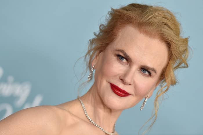 Reese smiling at a red carpet event while rocking a diamond necklace and earrings with an updo