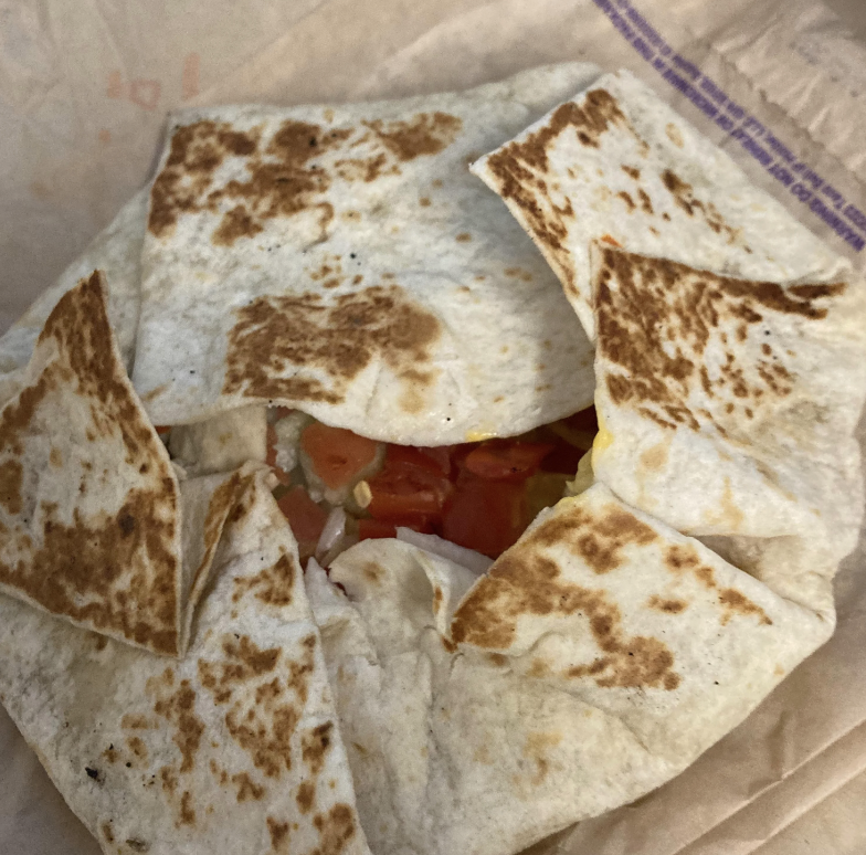 A folded tortilla wrap with visible fillings of rice, beans, and tomatoes