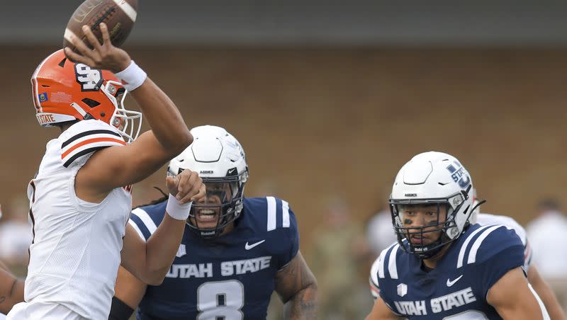 Idaho State quarterback Jordan Cooke throws a pass next to Utah State defensive tackle Hale Motu’apuaka (8) and defensive end Paul Fitzgerald (32) during a game Saturday, Sept. 9, 2023, in Logan, Utah. The Aggies face Air Force Friday night in Colorado Springs.