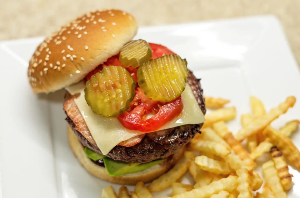 A homemade hamburger with pickles, cheese, and tomato.
