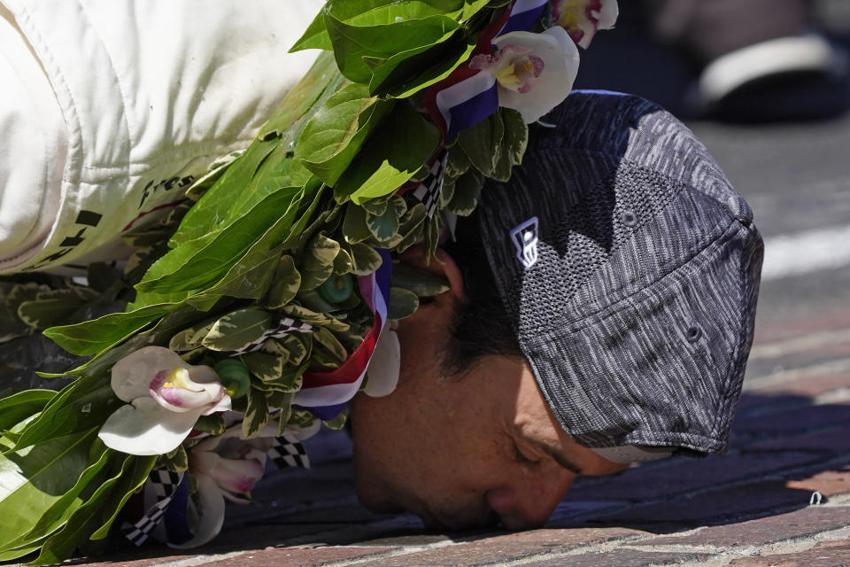 Helio Castroneves, of Brazil, kisses the yard of bricks at the start/finish line as he celebrates after winning after winning the Indianapolis 500 auto race at Indianapolis Motor Speedway, Sunday, May 30, 2021, in Indianapolis. (AP Photo/Paul Sancya)