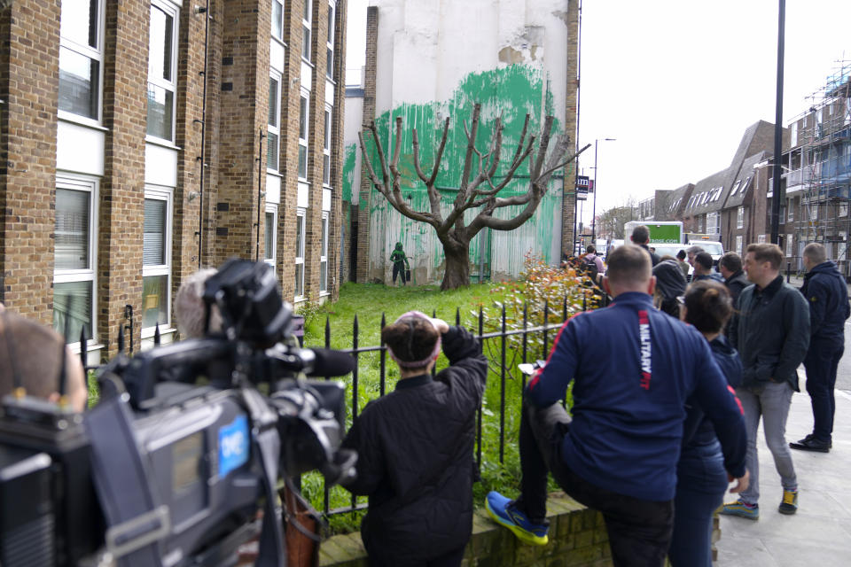 Personas miran un nuevo mural de Banksy en una pared en Londres, el lunes 18 de marzo de 2024. Un nuevo mural de Banksy en el vecindario de Finsbury Park atrajo multitudes a una calle de Londres el lunes, incluso antes de que el esquivo artista de graffiti confirmara que la obra era suya. (Foto AP/Alastair Grant)