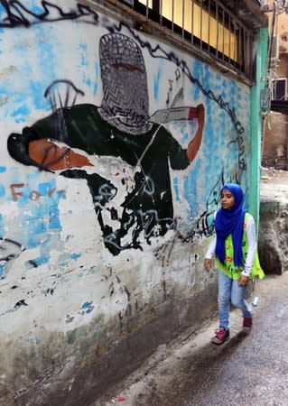 A girl walks past graffiti at Burj al-Barajneh refugee camp in Beirut