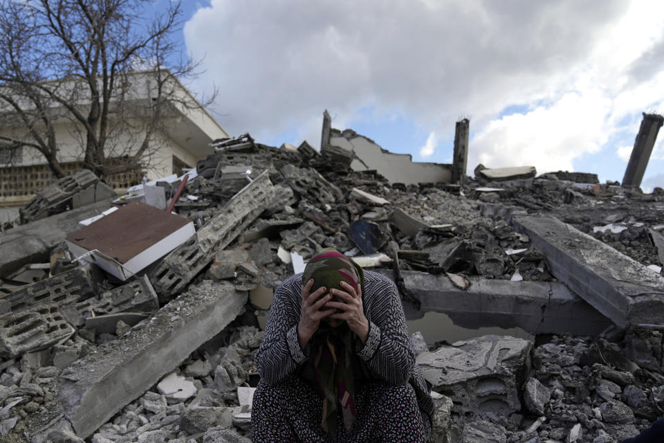 FILE - A woman sits on the rubble as emergency rescue teams search for people under the remains of destroyed buildings in Nurdagi town on the outskirts of Osmaniye city southern Turkey, Tuesday, Feb. 7, 2023. The 2011 quake, tsunami and nuclear meltdown in northern Japan provides a glimpse of what Turkey and Syria could face in the years ahead. No two events are alike, but the recent disaster resembles Japan's in the sheer enormity of the psychological trauma, of the loss of life and of the material destruction. (AP Photo/Khalil Hamra, File)