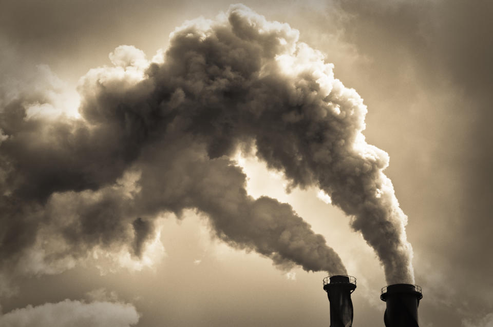 Toned monchrome image with billowing smoke coming from two chimneys.  Please note that limited film grain has been added during image processing.