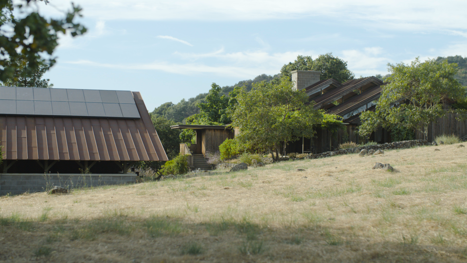 Outside of their home, with the solar panels on the rooftop.