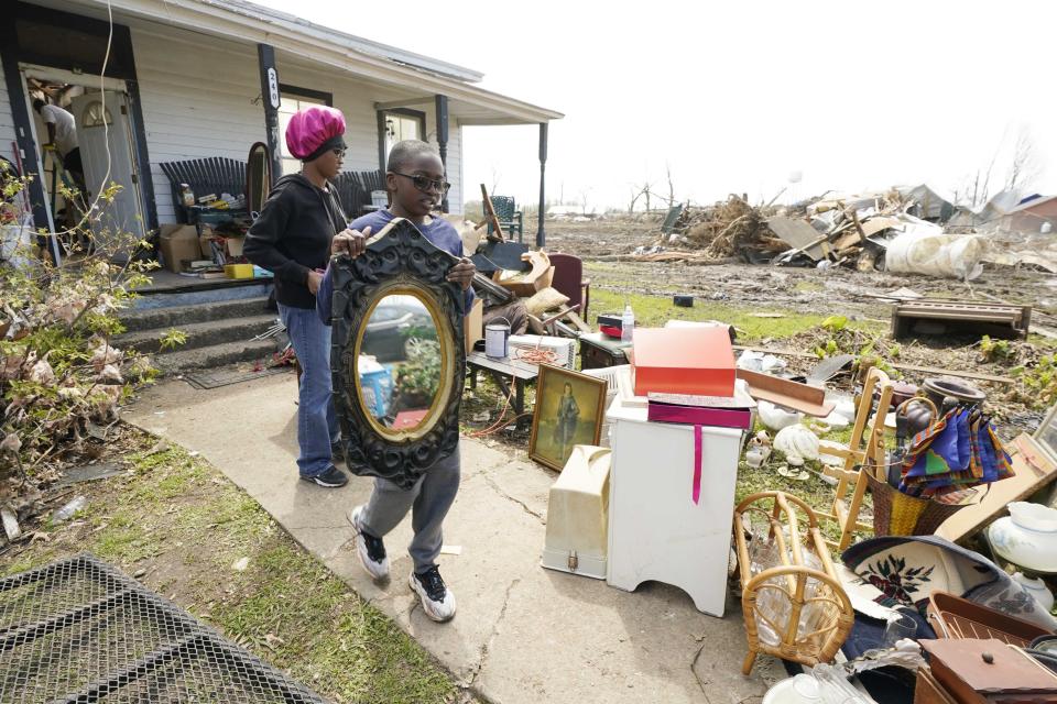 Jalandria Ellis Isola, left, and Jyran Kitchen, relatives of longtime Silver City, Miss., resident Mary Kitchen, carry out salvageable items, Tuesday, March 28, 2023. The home, like many hit by Friday's tornado in the Mississippi Delta, sustained severe damage. (AP Photo/Rogelio V. Solis)