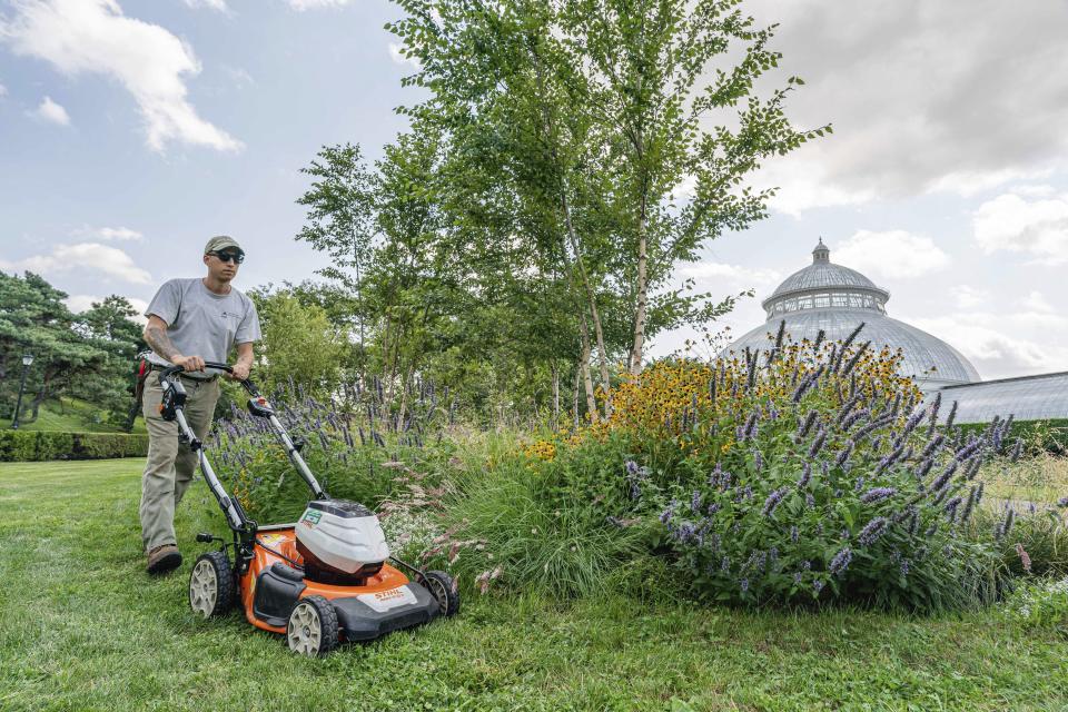 This undated image released by the New York Botanical Garden shows Tyler Campbell mowing the grounds in front of the Enid A. Haupt Conservatory at the New York Botanical Garden in the Bronx borough of New York. (Marlon Co/New York Botanical Garden via AP)