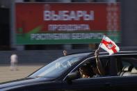 People in a car hold national flag as they take part in a flash mob ahead of presidential elections in Minsk, Belarus, Saturday, Aug. 8, 2020. On Saturday evening, police arrested at least 10 people as hundreds of opposition supporters drove through the center of the capital waving flags and brandishing clenched-fist victory signs from the vehicles' windows. The presidential election in Belarus is scheduled for August 9, 2020. (AP Photo/Sergei Grits)