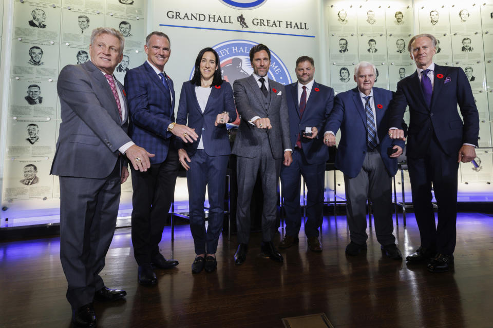 Hockey Hall of Fame 2023 inductees show of their rings during ceremonies Friday, Nov. 10, 2023, in Toronto. From left are Mike Vernon, Pierre Turgeon, Caroline Ouellette, Henrik Lundqvist, Eric Lacroix (son of inductee Pierre Lacroix), Ken Hitchcock, and Tom Barrasso. (Cole Burston/The Canadian Press via AP)