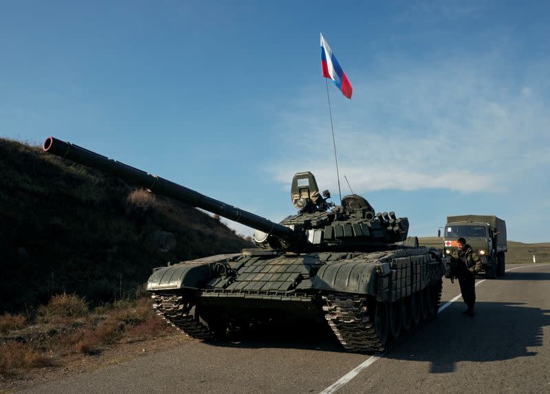 A service member of the Russian peacekeeping troops stands next to a tank in Nagorno-Karabakh