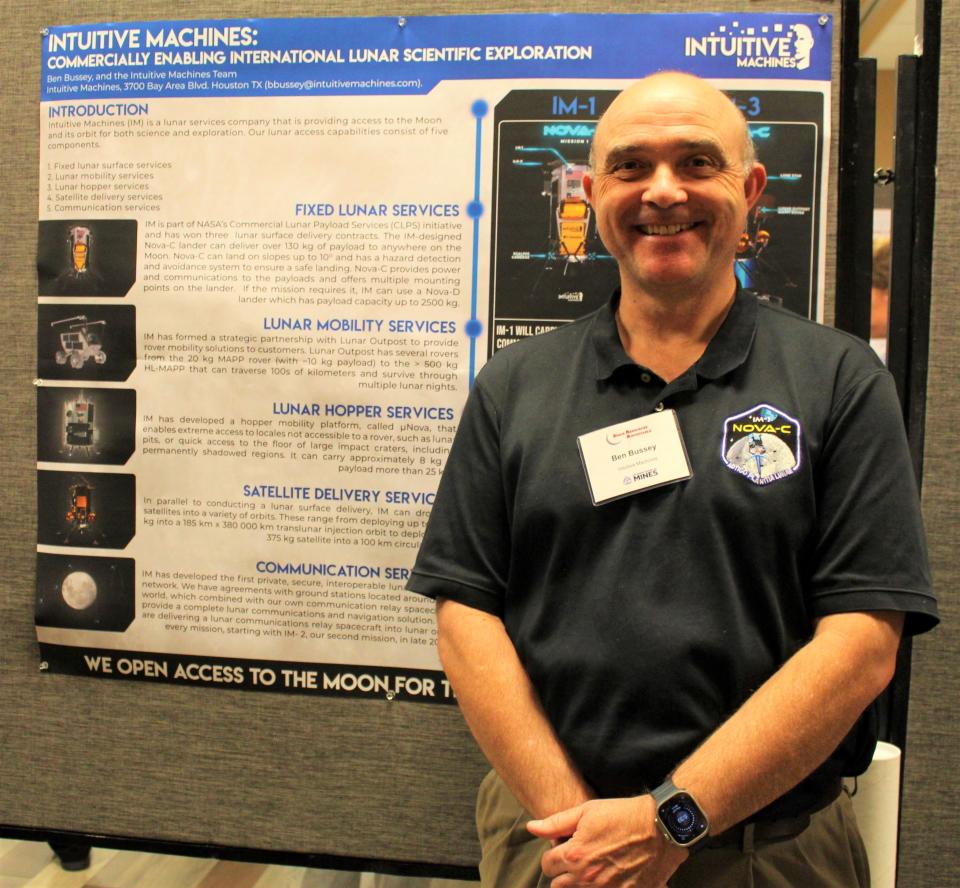 A bald man is standing in front of a science display.