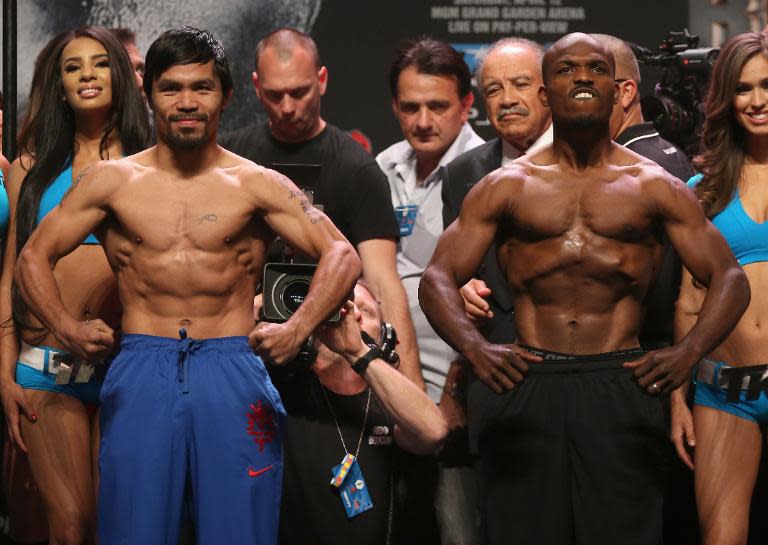 Manny Pacquiao and Timothy Bradley flex their muscles during a weigh-in prior to their welterweight world title bout in Las Vegas on April 11, 2014